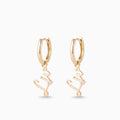 Gold huggie hoop earrings with a script name charm and a tiny stone