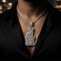 The Monogram Pendant worn on a Cuban link chain over a black silk shirt