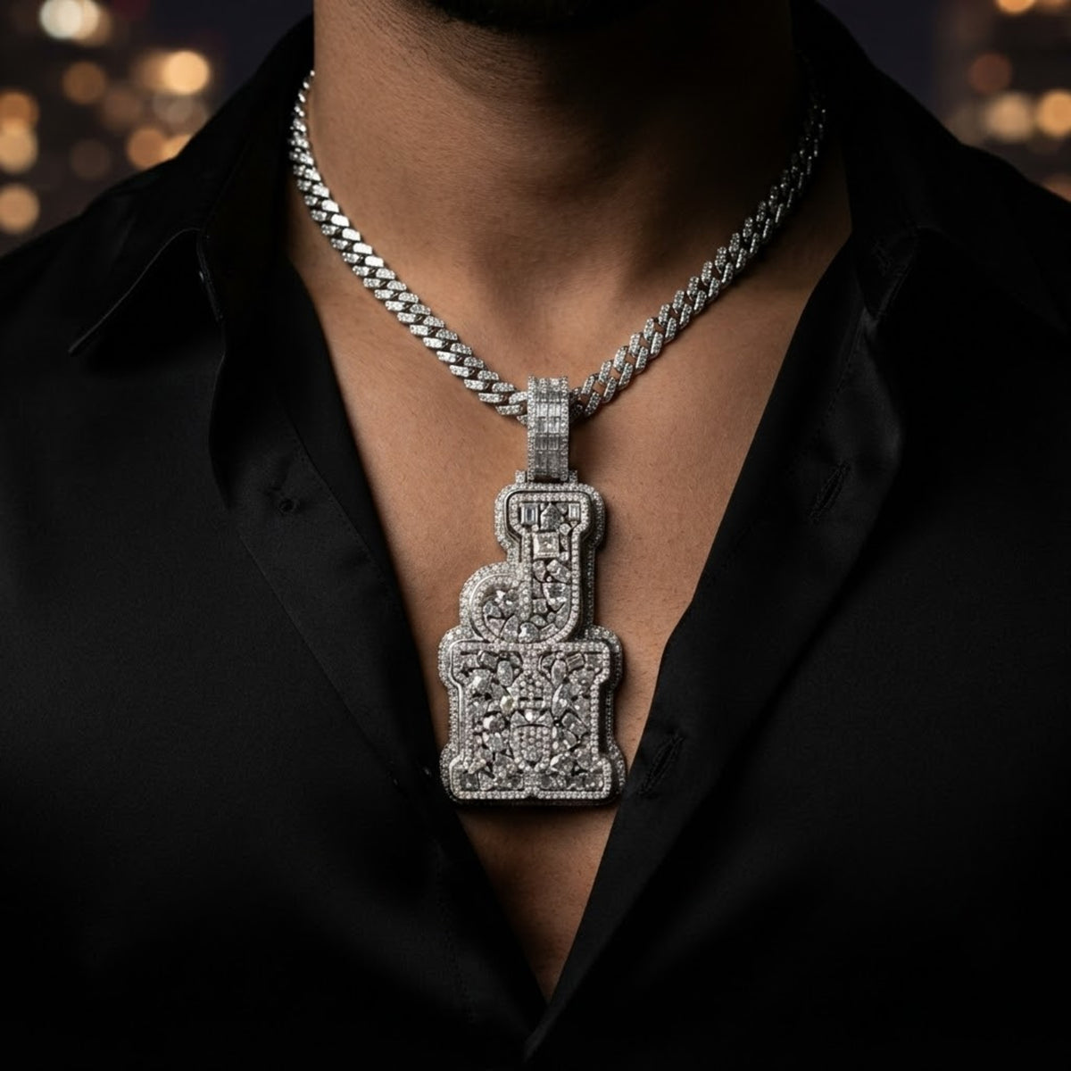 The Monogram Pendant worn on a Cuban link chain over a black silk shirt